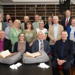 A group of people posing in a historic Library, with the two volumes of the first edition of Gulliver's travels set out on the table in front of them.