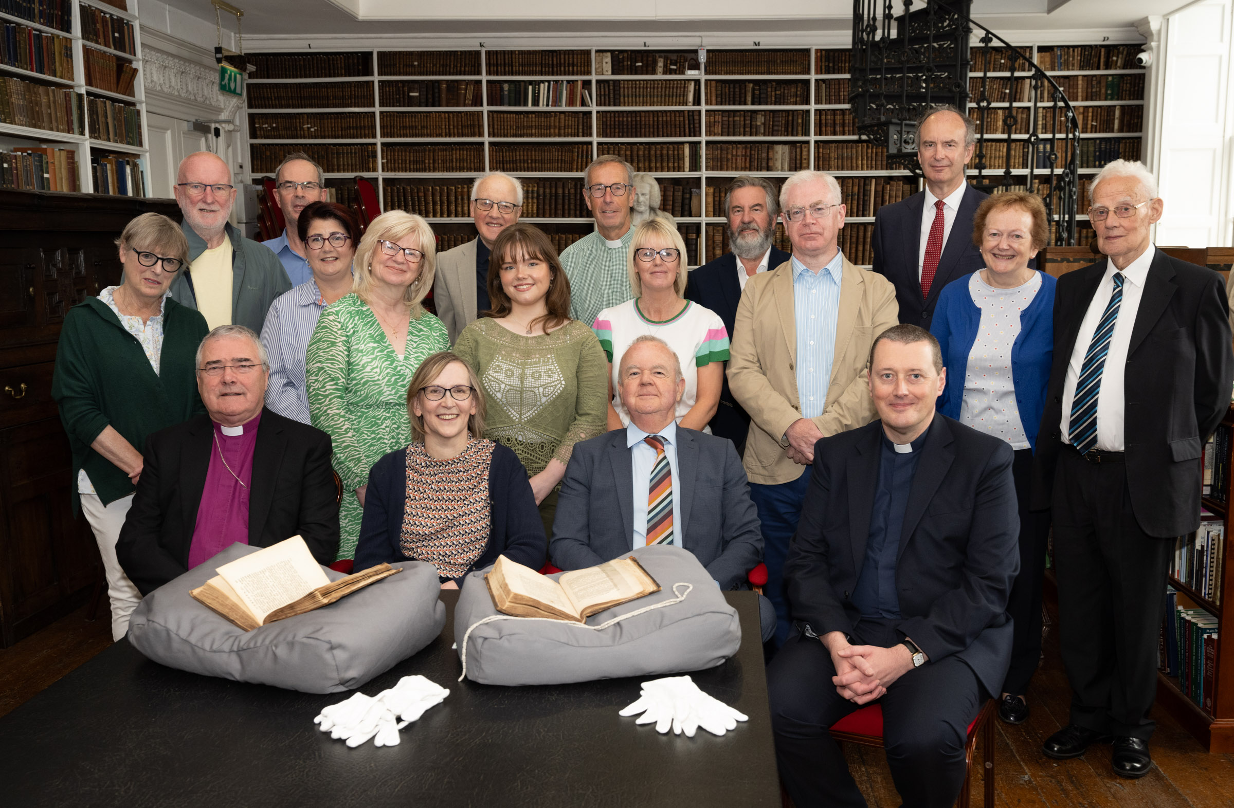 A group of people posing in a historic Library, with the two volumes of the first edition of Gulliver's travels set out on the table in front of them.